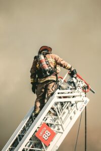 A fireman climbing up the ladder of a fire truck